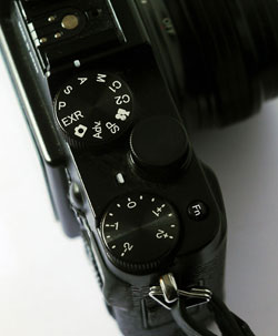 On this camera, a Fujifilm X10, the dial below the exposure mode control is the very easy-to-use exposure compensation control.
